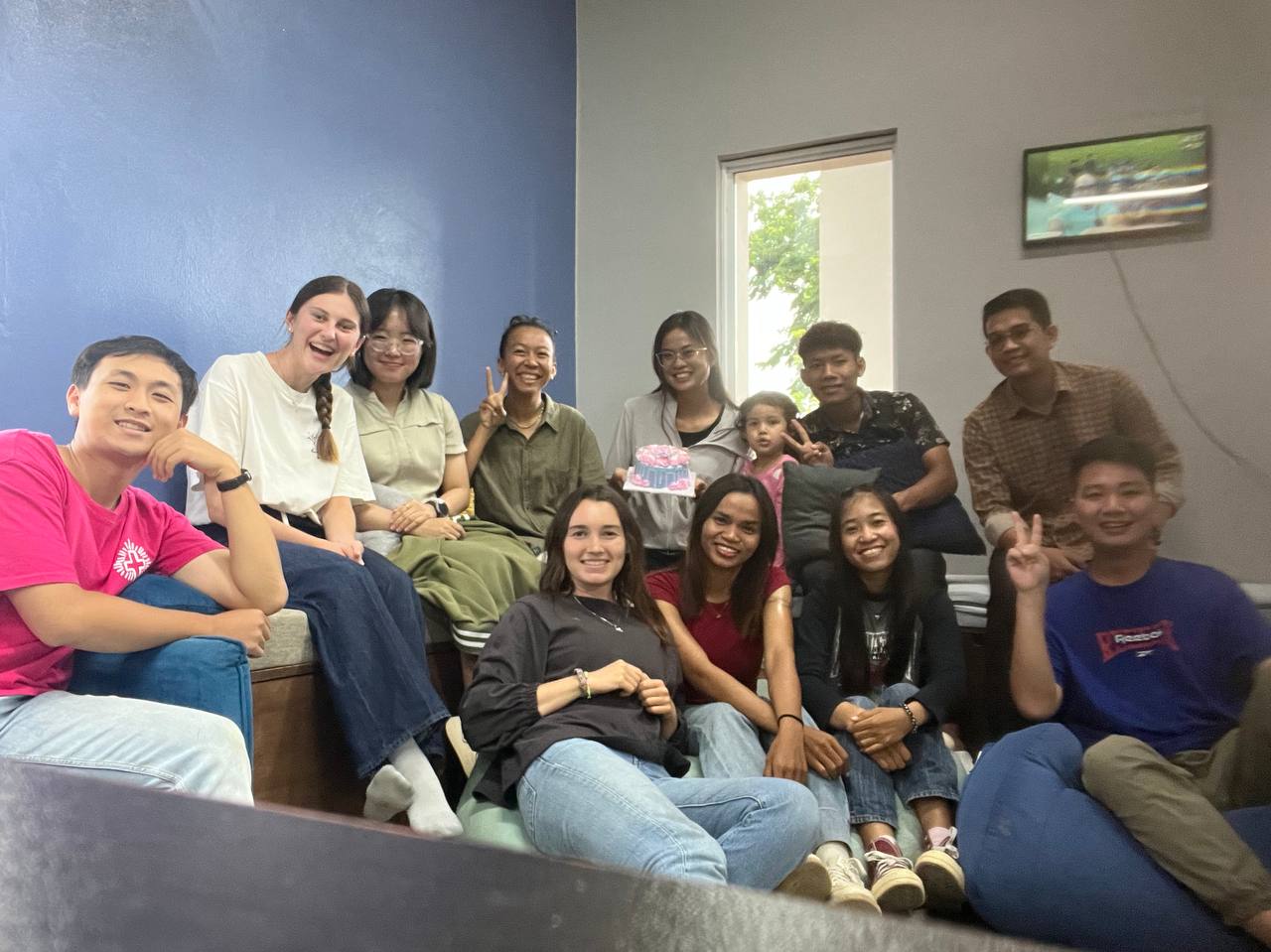 Brieya celebrating with a group of friends and teammates indoors, one holding a decorated cake.