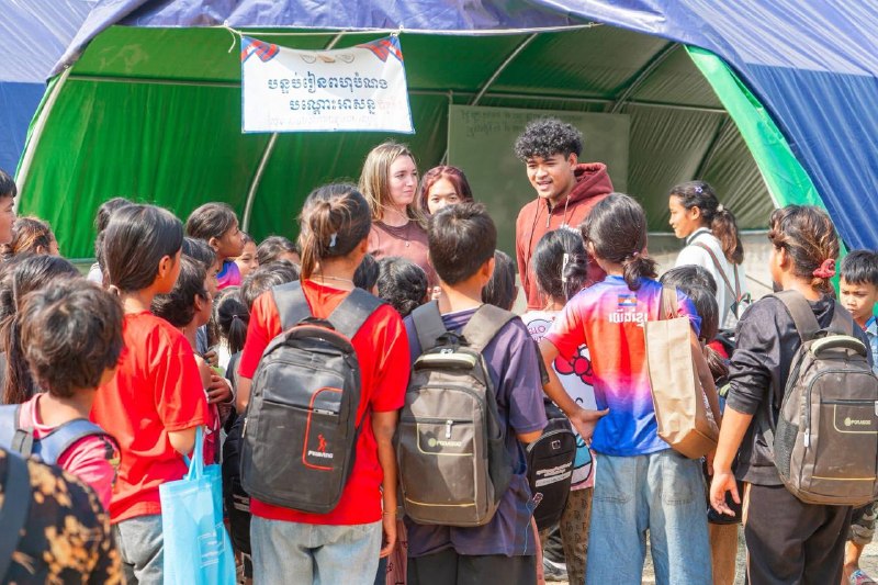 Brieya and a ministry teammate talking with a group of children gathered outside a tent.