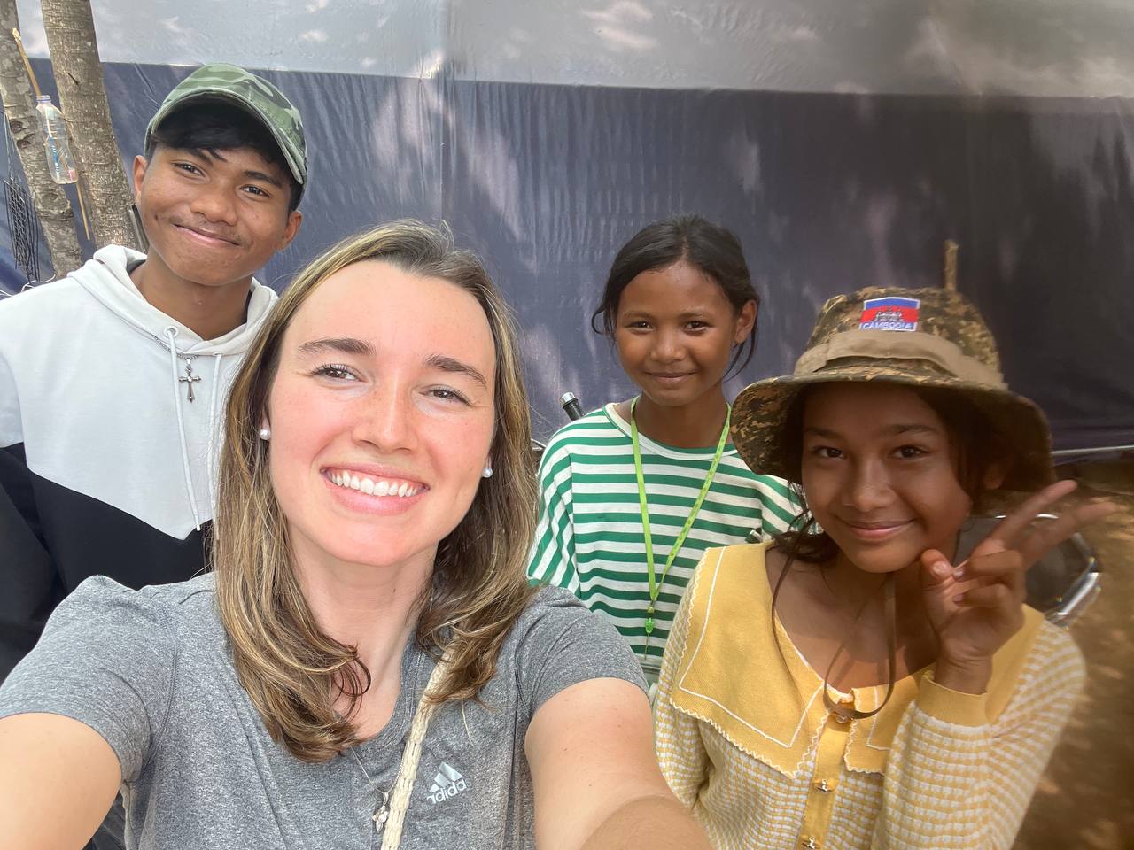 Brieya taking a selfie with three Cambodian youth in front of a ministry tent.